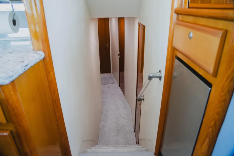 Slide: The Image of Interior hallway of a 1999 Viking 58 Convertible yacht, featuring wooden cabinetry and carpeted stairs. - 59