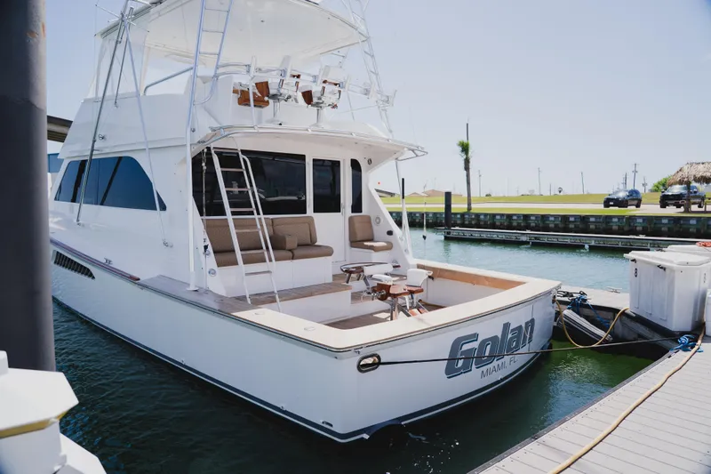 Slide: The Image of 1999 Viking 58 Convertible yacht docked, featuring spacious deck and seating area. - 6