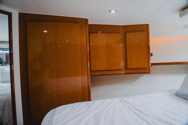 Slide: The Image of Interior of 1999 Viking 58 Convertible yacht with wooden cabinets and cozy bedding. - 62