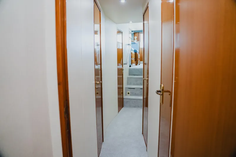 Slide: The Image of Hallway inside 1999 Viking 58 Convertible yacht, featuring wooden doors and carpeted flooring. - 65