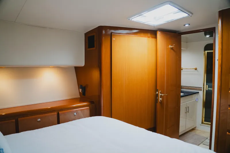 Slide: The Image of Interior of 1999 Viking 58 Convertible yacht bedroom with wooden cabinetry and open bathroom door. - 69