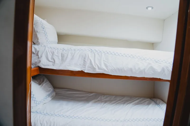 Slide: The Image of Bunk beds in 1999 Viking 58 Convertible yacht cabin, featuring white linens and wooden frames. - 78