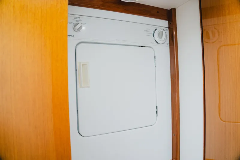 Slide: The Image of Laundry appliance inside 1999 Viking 58 Convertible yacht, featuring wooden cabinetry. - 83