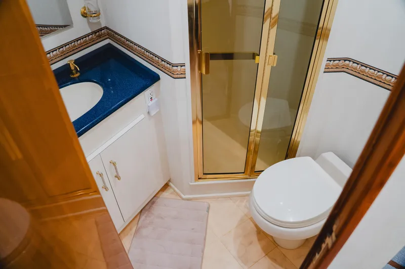 Slide: The Image of Bathroom interior of 1999 Viking 58 Convertible yacht with blue countertop and gold accents. - 84