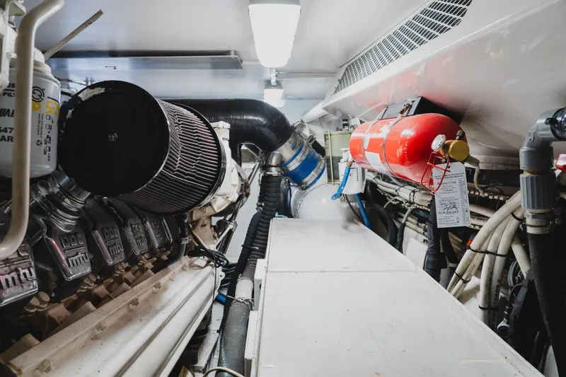 Slide: The Image of Engine room of a 1999 Viking 58 Convertible yacht, featuring machinery and fire extinguisher. - 94