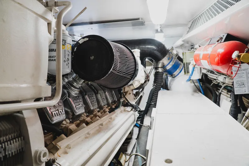 Slide: The Image of Engine room of a 1999 Viking 58 Convertible yacht, featuring mechanical components and fire extinguisher. - 98