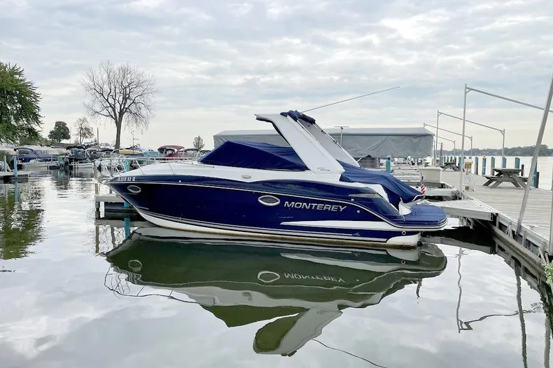 The Image of 2017 Monterey 275 Sport Yacht docked at a marina, reflecting on calm water. - 0