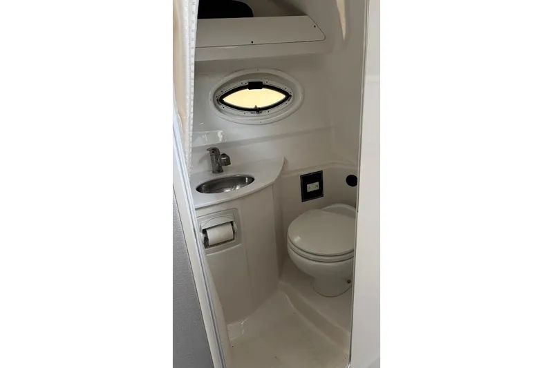 Slide: The Image of Compact bathroom in 2018 Monterey 275 Sport Yacht with sink, toilet, and porthole window. - 26