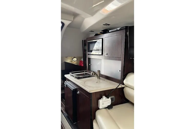 Slide: The Image of Interior of 2018 Monterey 275 Sport Yacht featuring a compact kitchenette with sink and microwave. - 27