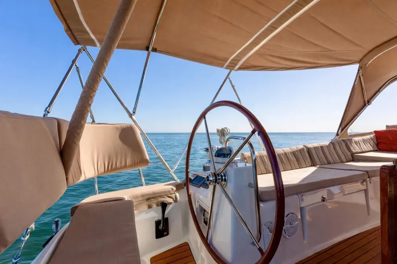 Slide: The Image of Cockpit of 2015 Jeanneau 53 sailboat with cushioned seating and steering wheel, ocean view. - 13