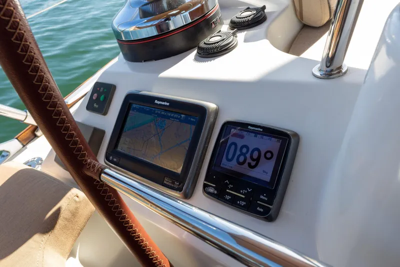 Slide: The Image of Navigation instruments on a 2015 Jeanneau 53 yacht, featuring Raymarine displays and a leather-wrapped steering wheel. - 16