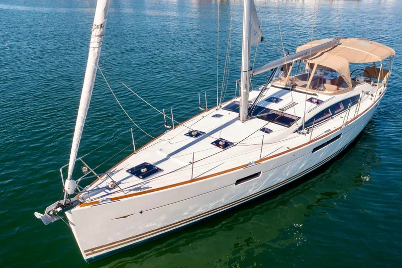 Slide: The Image of Jeanneau 53 sailboat from 2015 on serene water at sunset, coastal town backdrop. - 5