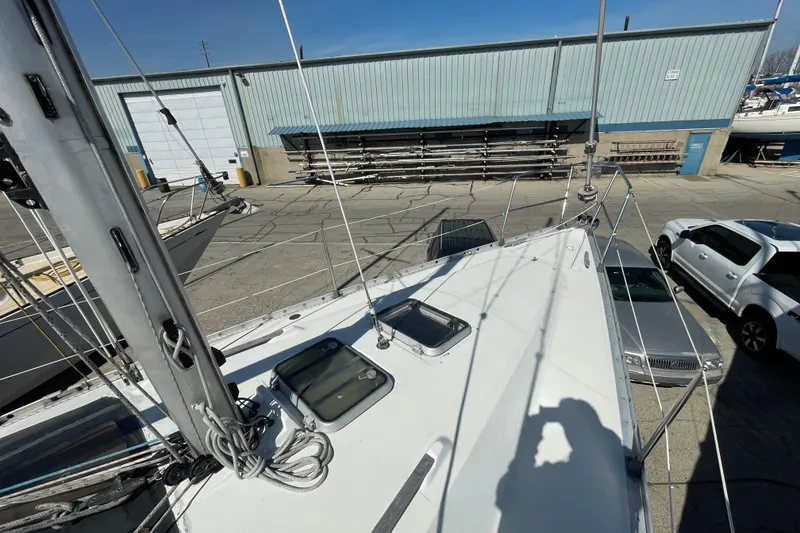 Slide: The Image of 1988 Beneteau Oceanis 350 sailboat docked near industrial building and parked vehicles. - 12