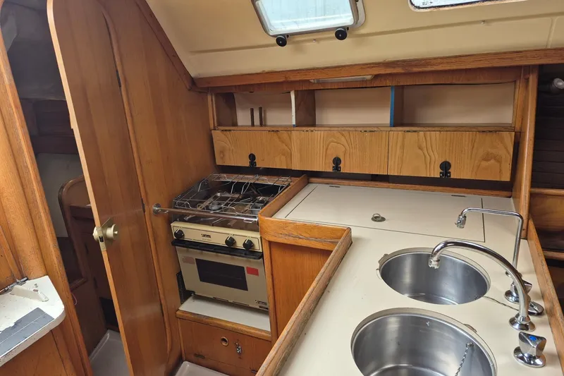Slide: The Image of Interior of 1988 Beneteau Oceanis 350 sailboat, featuring a compact kitchen with stove and dual sinks. - 15