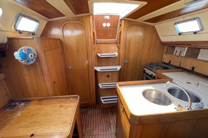 Slide: The Image of Interior of 1988 Beneteau Oceanis 350 sailboat with wooden cabinetry and compact kitchen. - 23