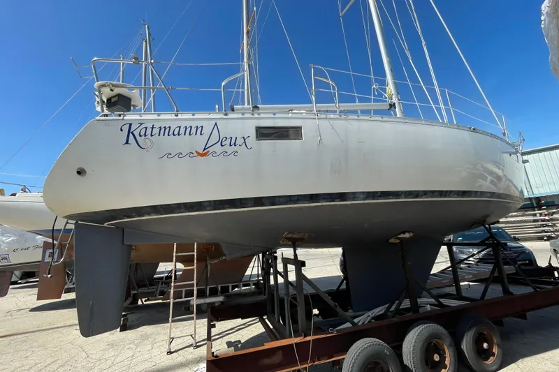 Slide: The Image of 1988 Beneteau Oceanis 350 sailboat on trailer, named "Katmann Deux," under clear blue sky. - 3