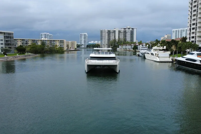 Slide: The Image of 2024 Sunreef 80 Power yacht cruising in a scenic urban waterway. - 2