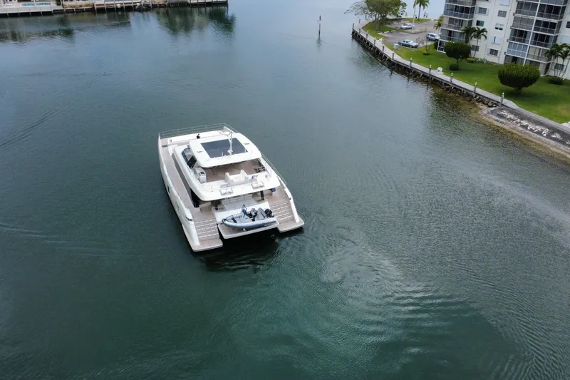 Slide: The Image of 2024 Sunreef 80 Power yacht cruising in a calm waterway near residential buildings. - 4