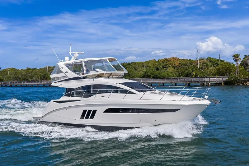 Slide: The Image of 2017 Sea Ray Fly 510 yacht cruising on blue water under a clear sky. - 12