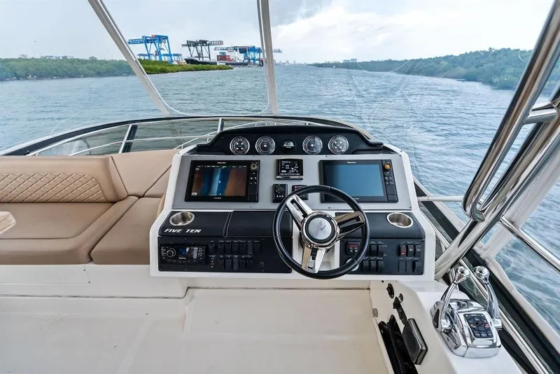 Slide: The Image of 2017 Sea Ray Fly 510 yacht helm with navigation screens and steering wheel on open water. - 44