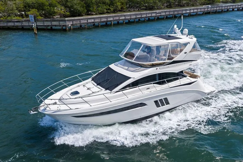 Slide: The Image of 2017 Sea Ray Fly 510 yacht cruising on blue water near a wooden dock. - 7