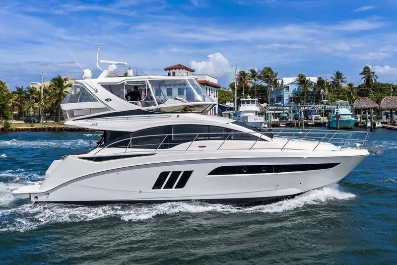 Slide: The Image of 2017 Sea Ray Fly 510 yacht cruising near a marina under a clear blue sky. - 9