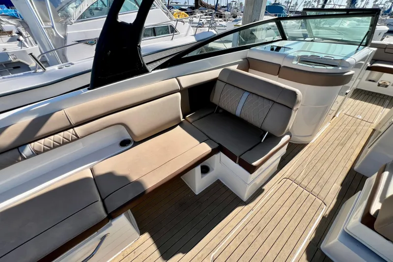 Slide: The Image of 2016 Sea Ray 290 Sundeck Outboard interior with beige seating and wooden deck. - 16