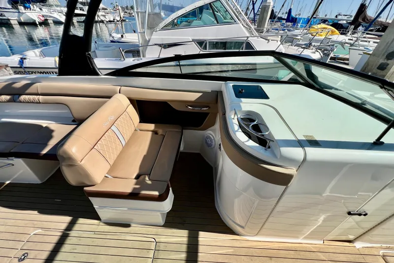 Slide: The Image of 2016 Sea Ray 290 Sundeck Outboard interior with tan seating and cup holders at marina. - 18