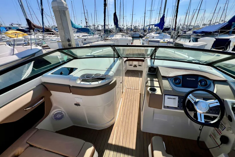 Slide: The Image of 2016 Sea Ray 290 Sundeck Outboard interior with steering wheel, dashboard, and marina view. - 19