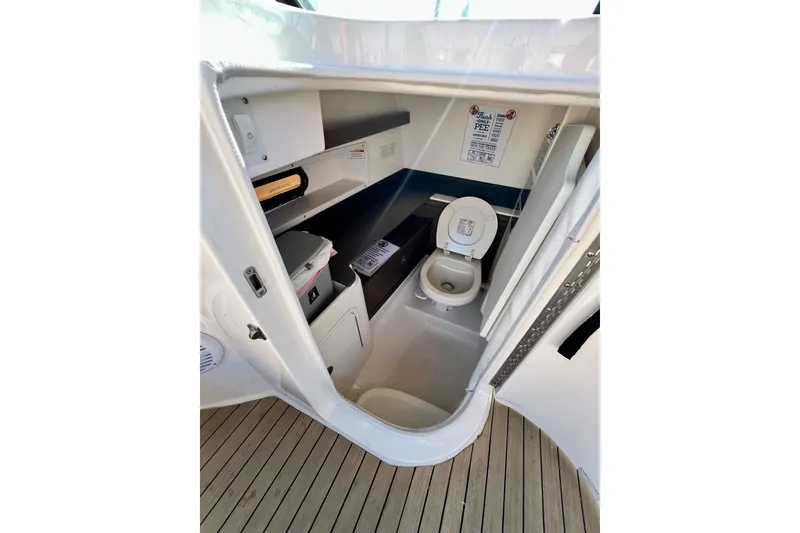 Slide: The Image of 2016 Sea Ray 290 Sundeck Outboard boat interior bathroom with toilet and storage shelves. - 20