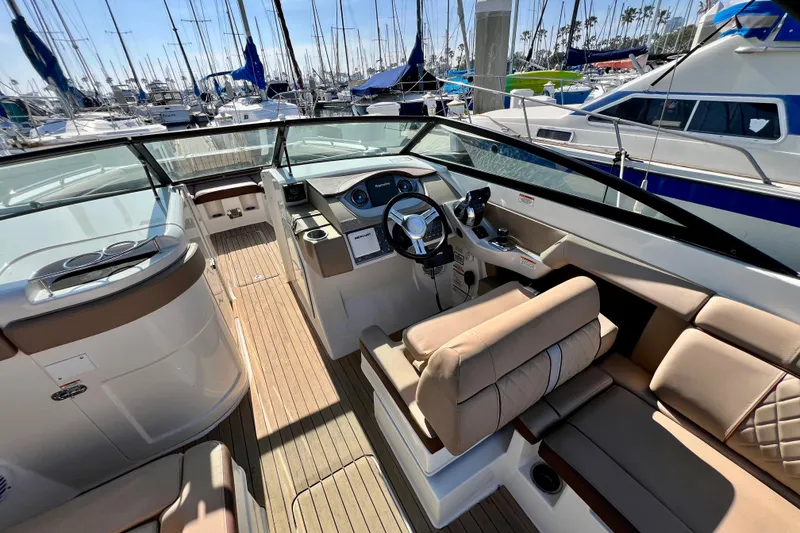 Slide: The Image of 2016 Sea Ray 290 Sundeck Outboard interior with helm, seating, and marina view. - 24