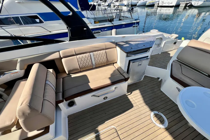 Slide: The Image of 2016 Sea Ray 290 Sundeck Outboard interior with beige seating and wooden deck. - 33