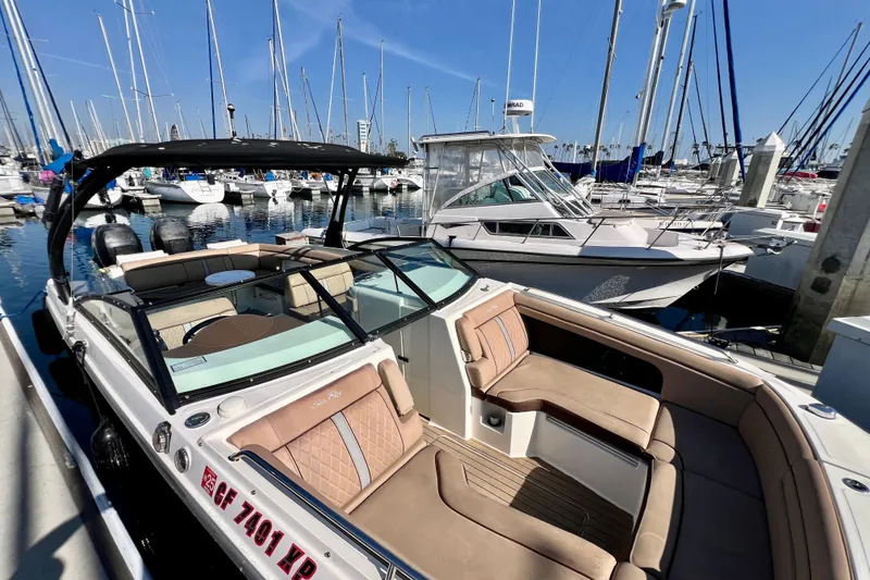 Slide: The Image of 2016 Sea Ray 290 Sundeck Outboard docked in a marina, surrounded by sailboats. - 6