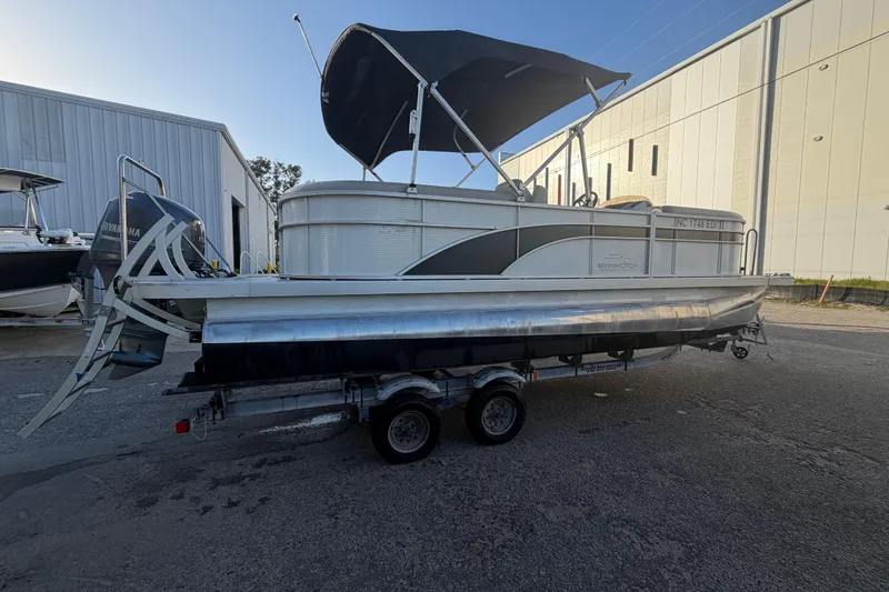 Slide: The Image of 2016 Bennington 22 SX pontoon boat on trailer, parked near industrial buildings. - 10