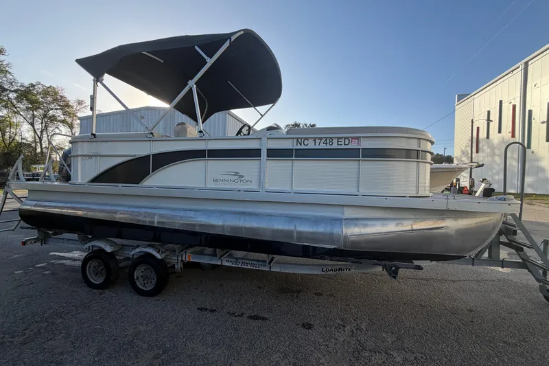 Slide: The Image of 2016 Bennington 22 SX pontoon boat with canopy on trailer, parked outdoors. - 12