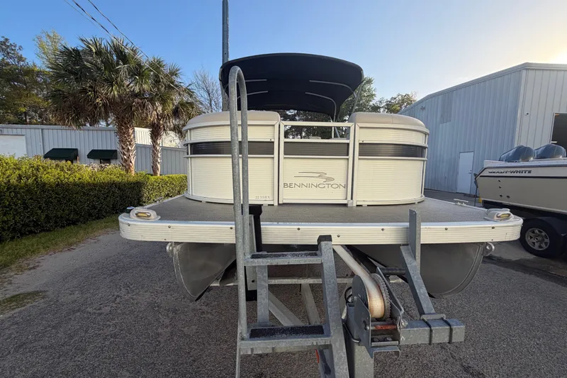 Slide: The Image of 2016 Bennington 22 SX pontoon boat on trailer, parked outdoors near palm trees. - 19