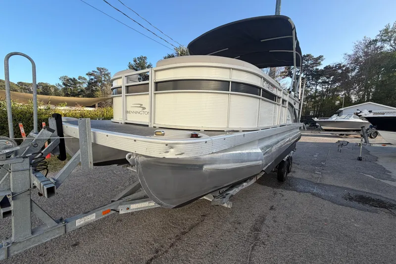Slide: The Image of 2016 Bennington 22 SX pontoon boat on trailer, parked outdoors under clear sky. - 20
