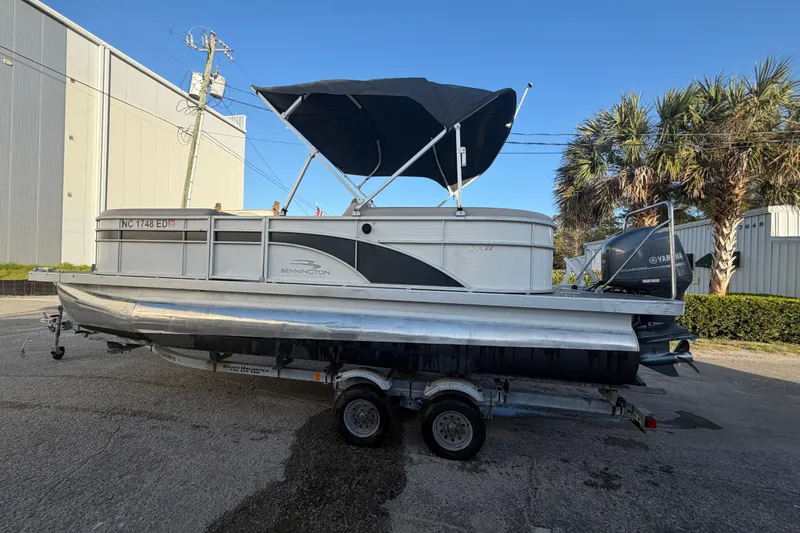 Slide: The Image of 2016 Bennington 22 SX pontoon boat on trailer with canopy, parked outdoors. - 27