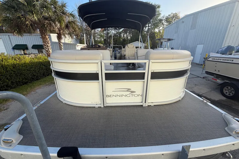 Slide: The Image of 2016 Bennington 22 SX pontoon boat with canopy, parked outdoors near palm trees. - 29