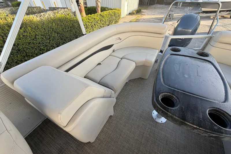 Slide: The Image of 2016 Bennington 22 SX pontoon boat interior with beige seating and black table. - 35