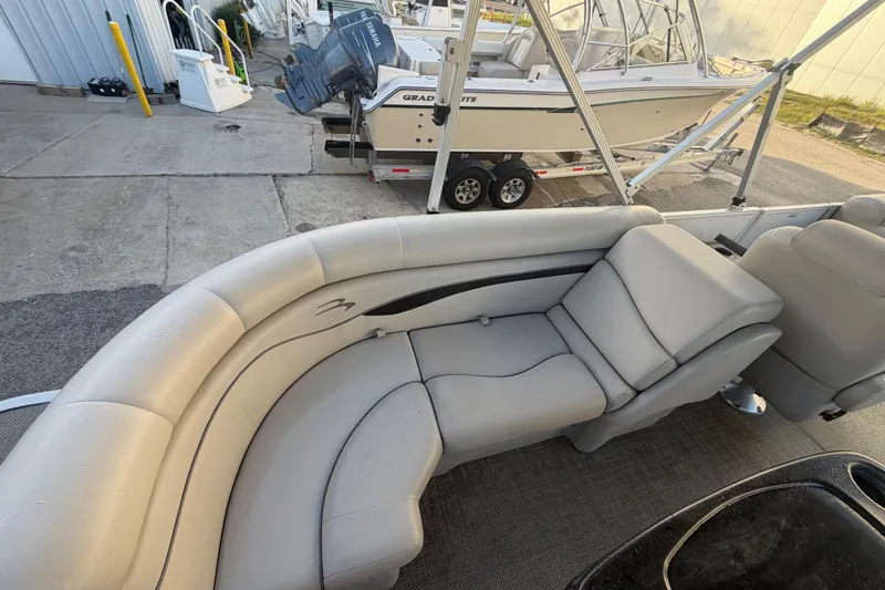 Slide: The Image of 2016 Bennington 22 SX boat interior with gray seating and nearby docked boats. - 43