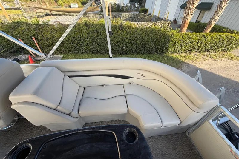 Slide: The Image of 2016 Bennington 22 SX pontoon boat with beige seating and outdoor view. - 44
