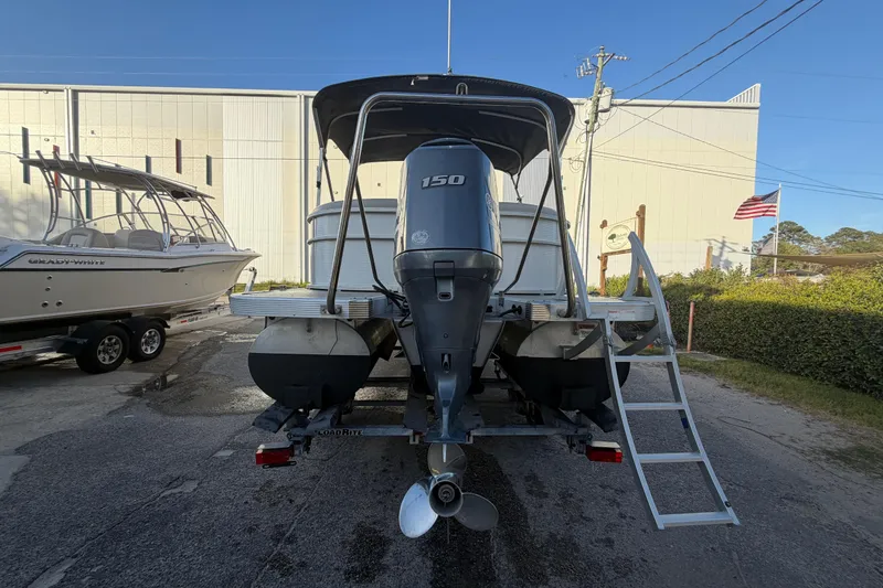 Slide: The Image of 2016 Bennington 22 SX pontoon boat with 150 HP engine, parked near a building. - 5