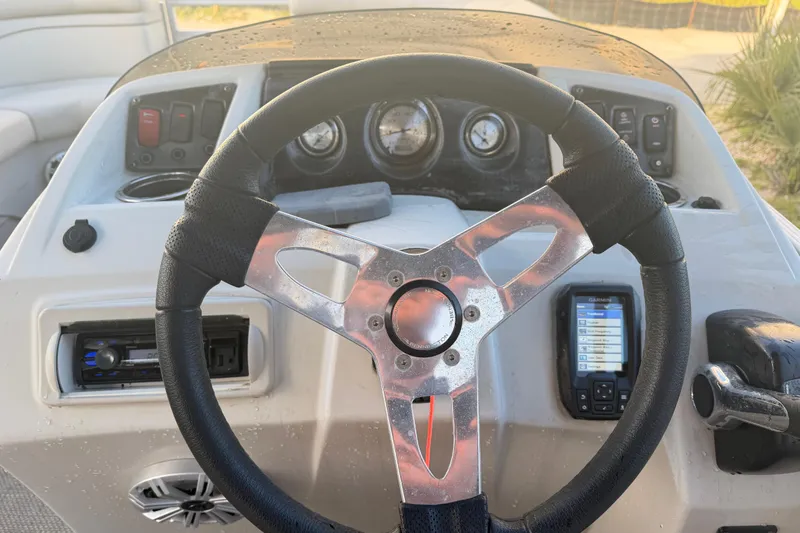 Slide: The Image of Steering wheel and dashboard of a 2016 Bennington 22 SX boat, featuring gauges and controls. - 66