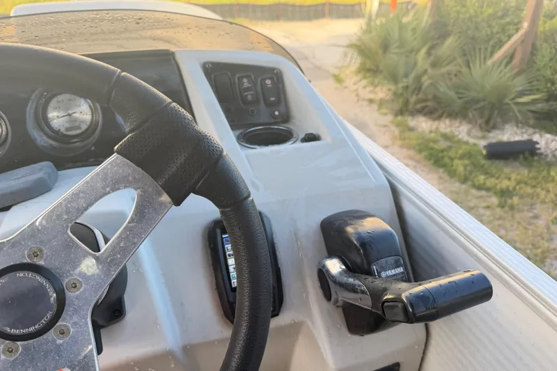 Slide: The Image of Steering wheel and controls of a 2016 Bennington 22 SX boat, featuring Yamaha throttle. - 68