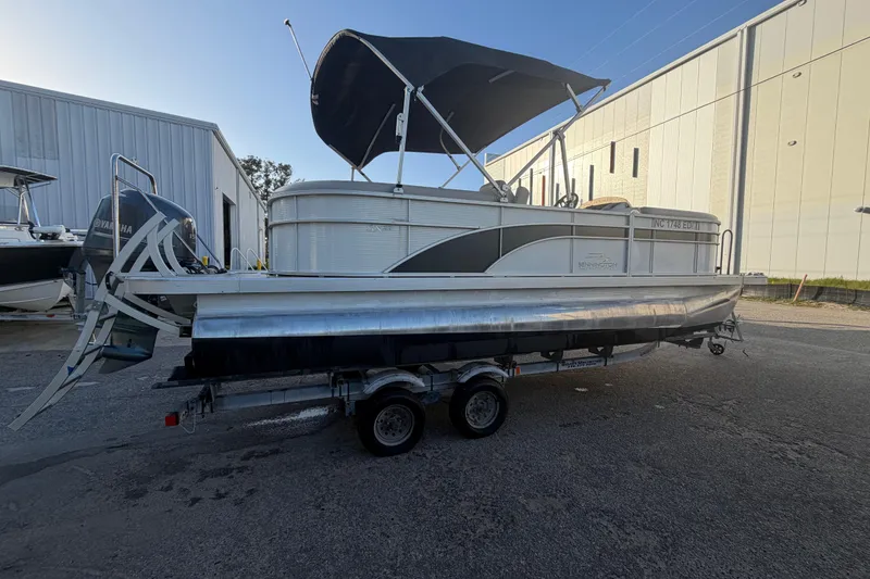 Slide: The Image of 2016 Bennington 22 SX pontoon boat on trailer, parked near industrial buildings. - 8