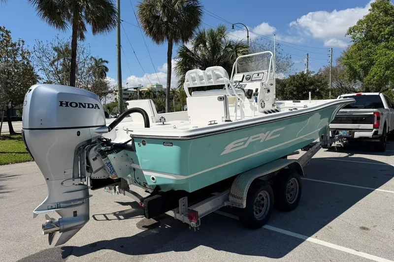 Slide: The Image of 2018 Epic 22SC boat with Honda outboard motor on trailer, parked under palm trees. - 3