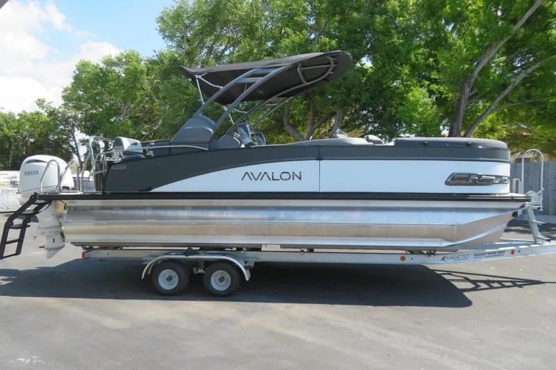 Slide: The Image of 2026 Avalon Catalina Quad Lounge Shift pontoon boat on trailer, parked outdoors. - 16