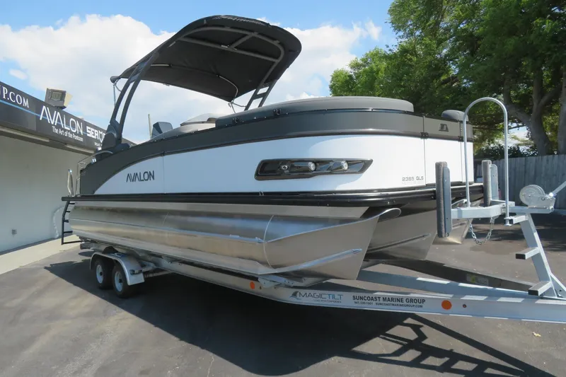 Slide: The Image of 2026 Avalon Catalina Quad Lounge Shift pontoon boat on trailer, parked outdoors. - 17
