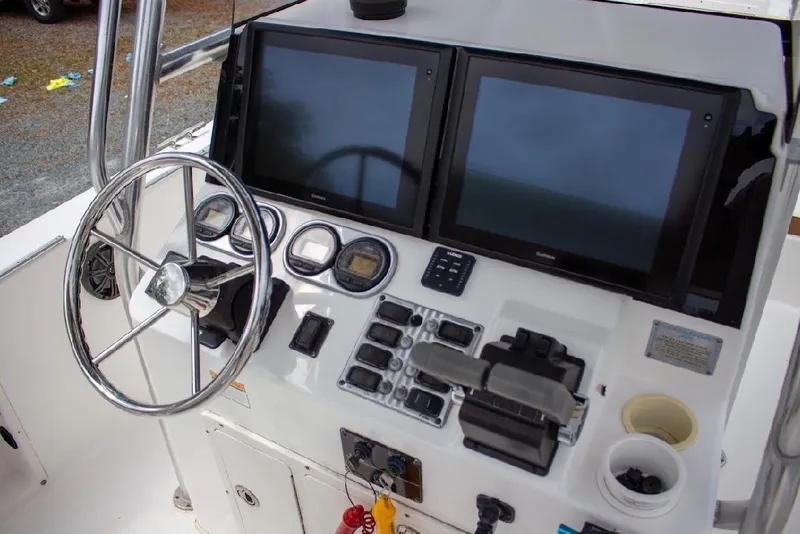 Slide: The Image of Center console of a 2001 Cobia 274 boat with dual screens and steering wheel. - 11